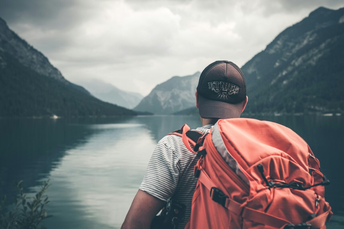 a guy with a red backpack on a lake